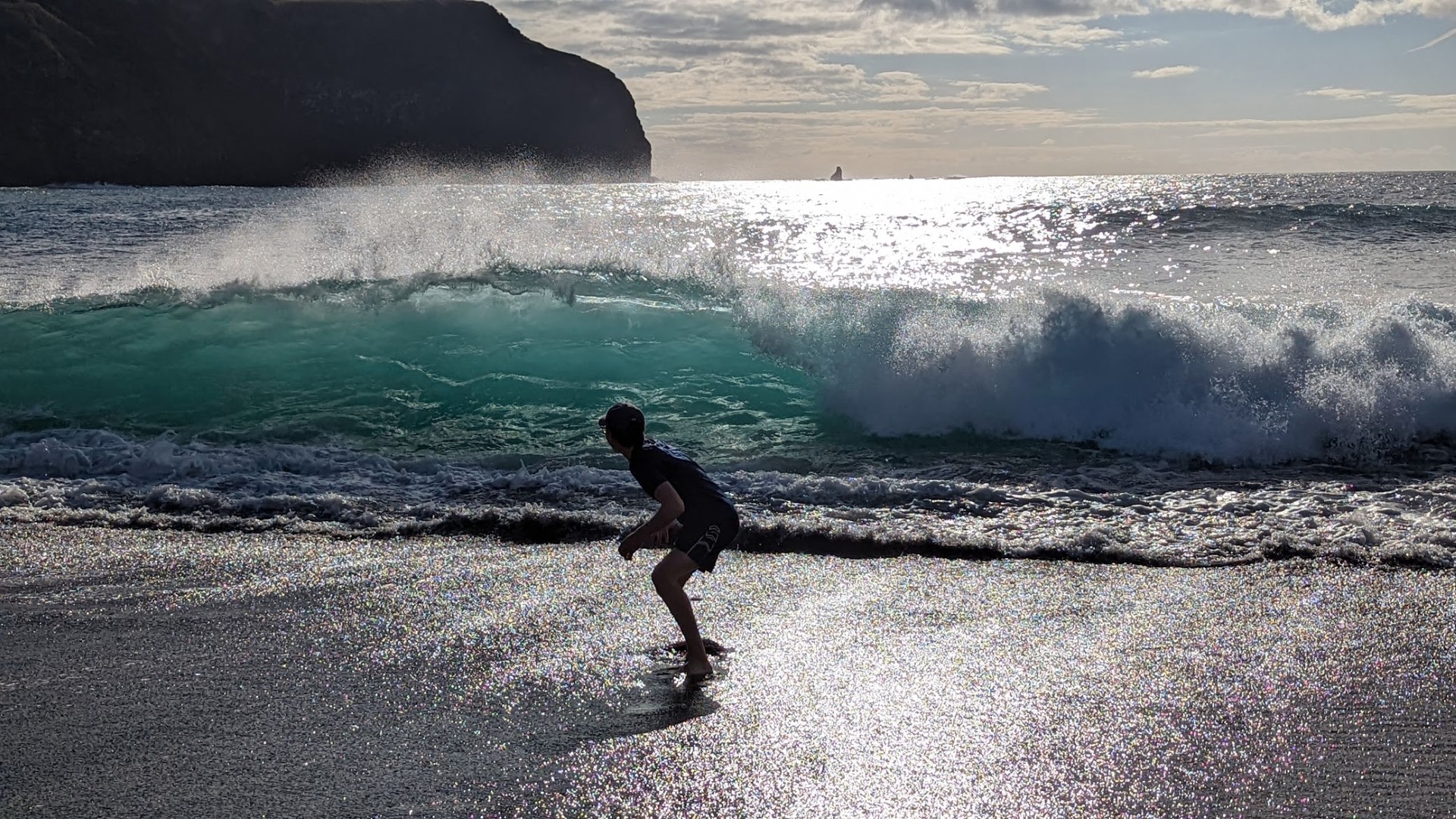 boy running from a wave on the beach