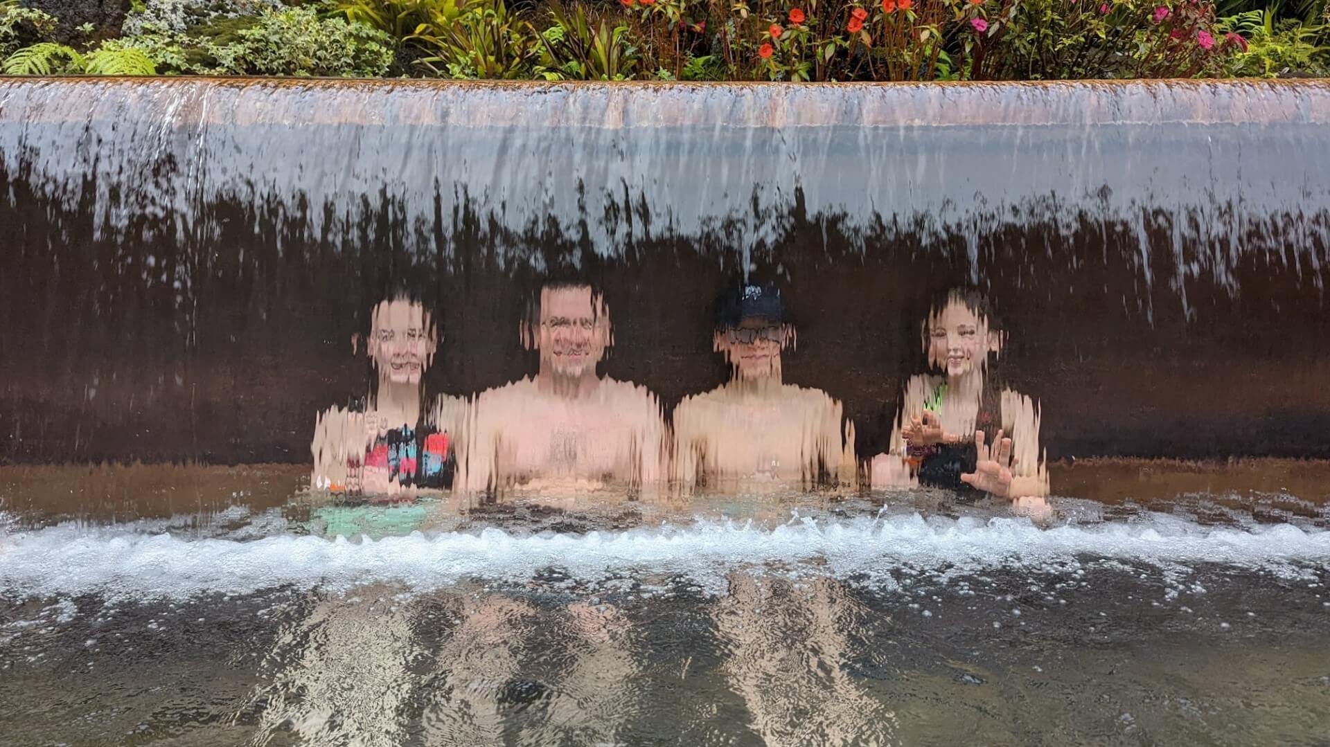 man and kids behind waterfall